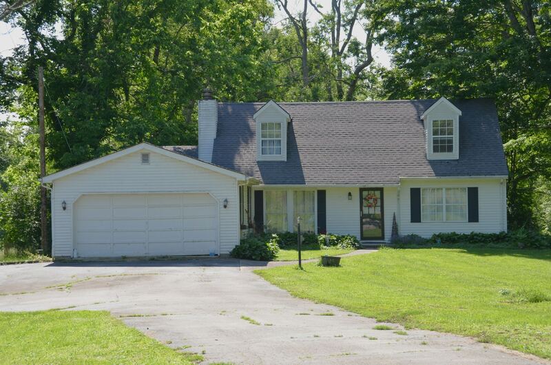 White Cape Cod style home with dormers and a raised-panel steel two-car garage door