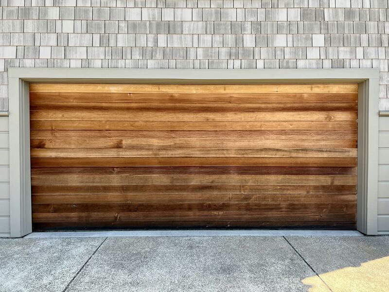 Close view of a horizontal cedar plank garage door set in shingle siding