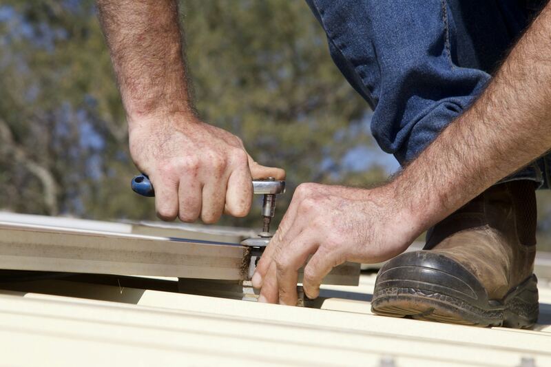 Close-up of work-worn hands tightening a bolt with a ratchet wrench